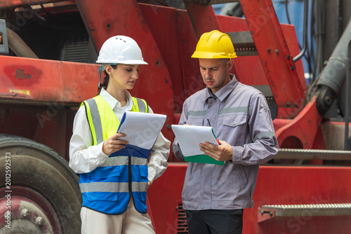 Two engineers discussing project together in construction site outdoors.