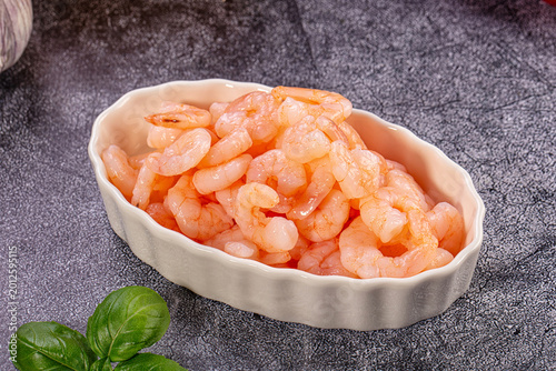 Cooked peeled shrimp in white bowl with fresh vegetables and herbs for cooking