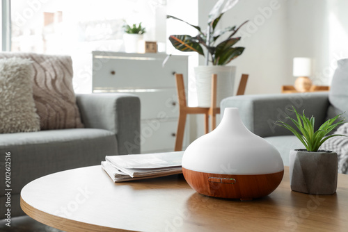 Foto Air humidifier with houseplant and magazines on coffee table in living room