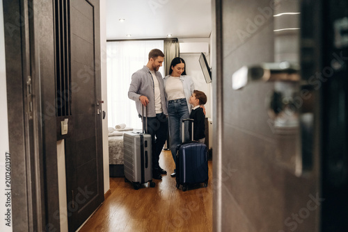 Canvastavla Family with luggage standing in hotel room doorway, modern decor visible, includ