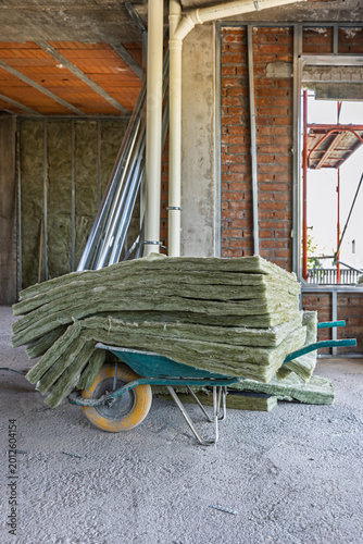 Fotografie Wheelbarrow carrying glass wool insulation at construction site