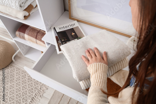 Woman putting sweaters into...