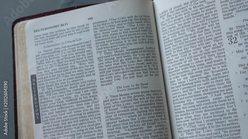 Holy Bible open up to the book of Deuteronomy of the old testament, zooming into Chapter 31 verse 6 on being strong and courageous. New Revised Standard Version.