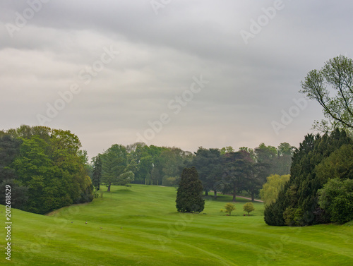 Scenic golf course landscape with lush green fairways and mature trees under overcast sky in Laeken, Brussels, Belgium