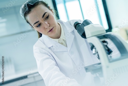 Young scientist works in laboratory using microscope for research on samples and observations in clinical setting