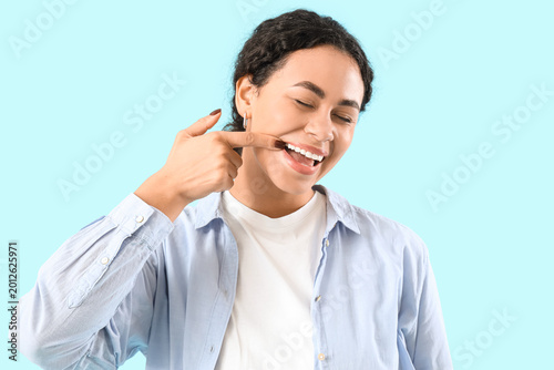 Bild auf Leinwand Young African-American woman showing her teeth on blue background, closeup