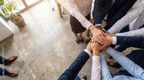 Top-down view of diverse business team huddling with hands together, symbolizing unity and collaboration.