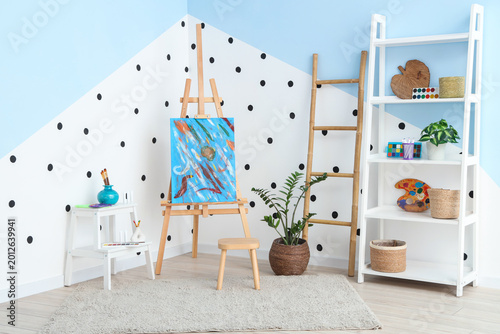 Foto Interior of artist's workshop with painting on easel, stepladder and art supplie