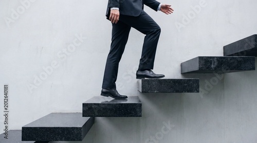 Tableau sur toile Businessman in a formal suit climbing up a modern concrete staircase, symbolizing career progress