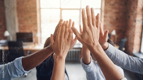Foto Business team celebrating success, showing hands in a high-five gesture inside a bright modern office environment