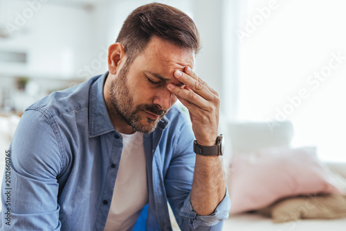 Photography Stressed Man With Headache Holding His Head in Living Room, Tired Adult With Mig
