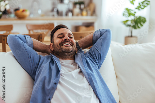 Quadro su tela Relaxed Smiling Man Reclining On Couch At Home Enjoying Leisure Time In Bright L