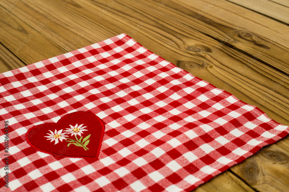 Obraz premium Red and white checkered tablecloth with heart design on wooden table during daylight