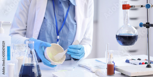 Young African-American female chemist with mortar and Petri dish working in l...