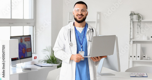 Male doctor with laptop analyzing scientific data in laboratory
