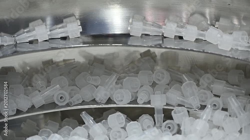 Automated blow feeder machine sorting clear plastic medical parts in a high-speed production line.