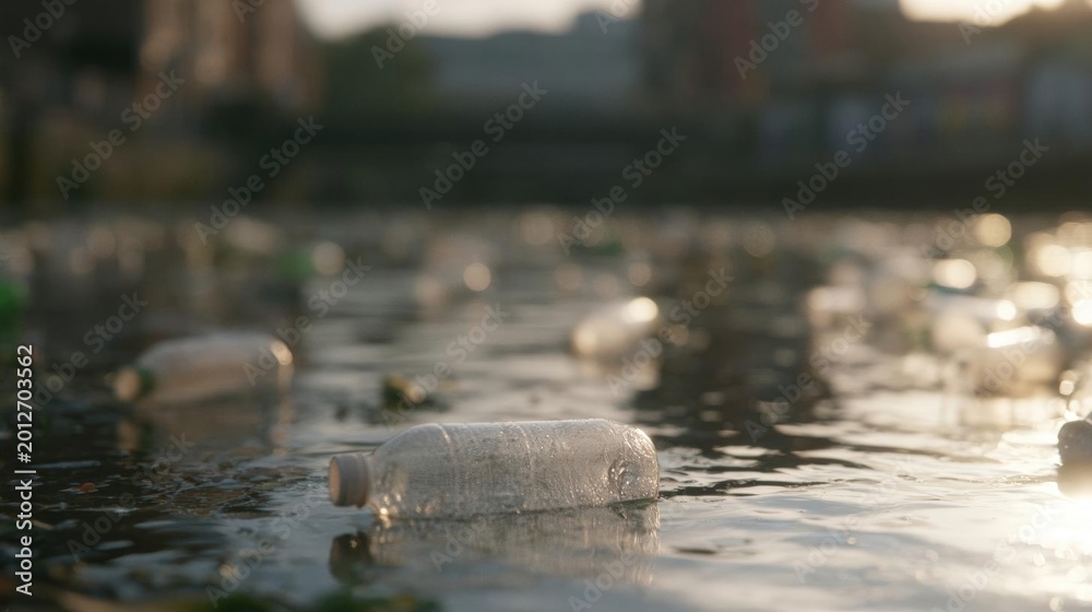 Fototapeta premium Group of empty plastic bottles floating on the surface of a body of water. the bottles are of different sizes and shapes, with some being larger and others smaller.