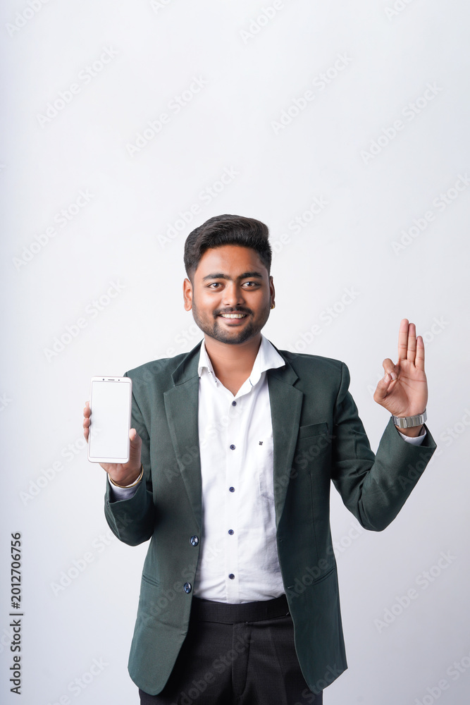 Fototapeta premium young indian businessman showing smartphone screen standing on white background