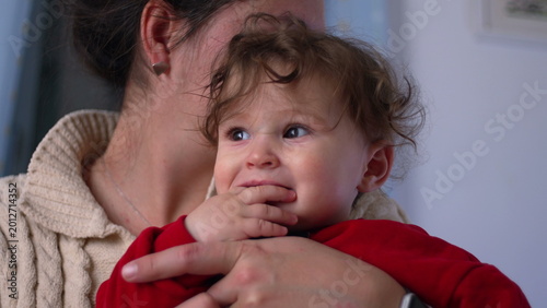 Принти на полотні Mother kissing baby close up, infant reacts with wide-eyed surprise and open mou