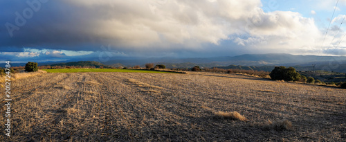 Canvas Print Harvested agricultural field under threatening storm sky