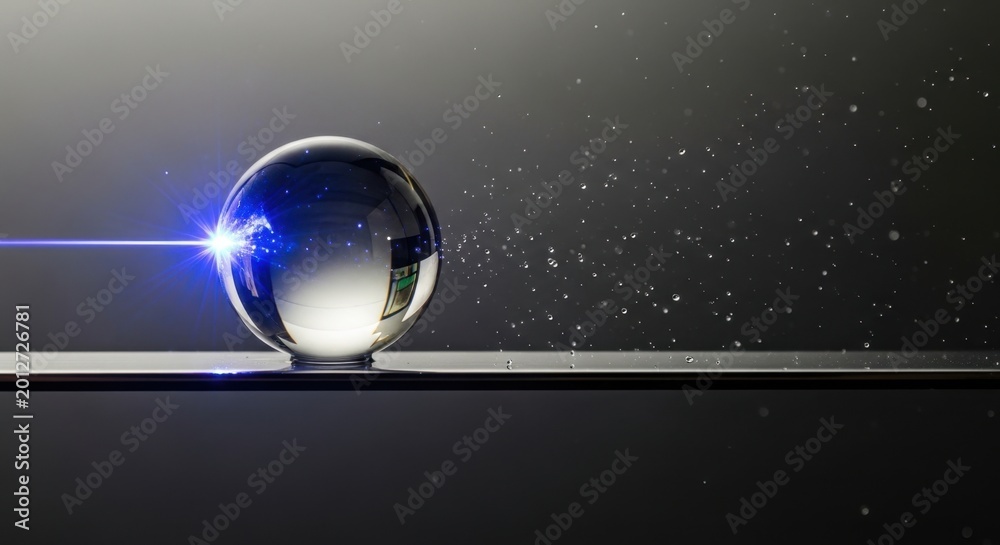 Fototapeta premium Laser beam hitting a crystal ball with water droplets