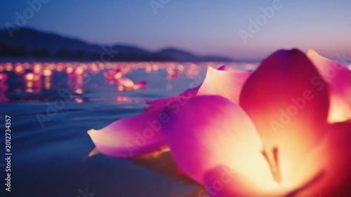 Beautiful pink lotus flower floating peacefully on dark water at dusk, surrounded by blurred glowing lights, creating a serene and spiritual atmosphere.