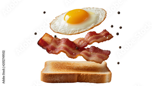 Obraz na płótnie Fried egg and bacon strips floating above toast, isolated on transparent backgro