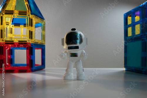 Toy astronaut figurine standing between colorful magnetic building blocks on a white surface, space exploration play concept