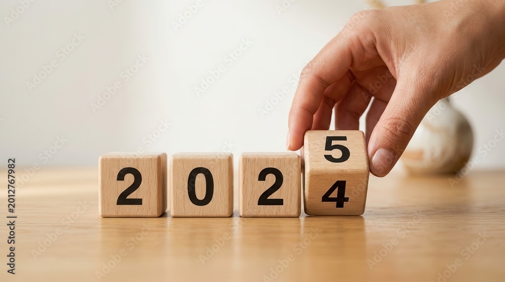 Naklejka premium A hand moving wooden blocks to change 2024 into 2025 representing new year investment and targets.