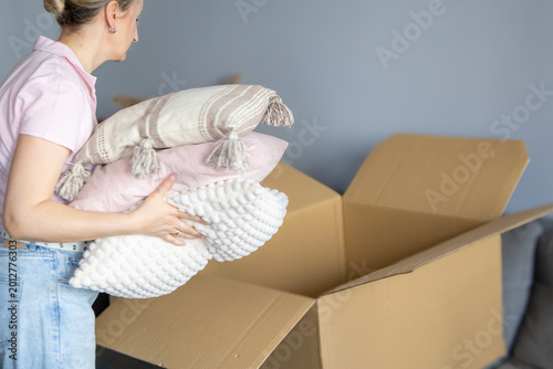 Tableau sur toile Middle aged woman packing clothes into cardboard box while preparing for apartment relocation