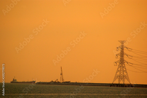 Coastal industrial estates and the hight voltage power line in the evening sunlight