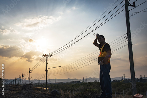 Fotografi Male electrical engineer wipe sweat on his forehead, outdoor utility pole inspec