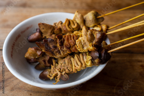 Foto Close up of traditional Indonesian chicken offal satay featuring liver, gizzard, and intestine served on bamboo skewers in a bowl