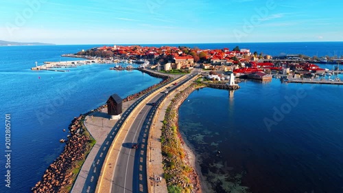 Causeway bridge connecting mainland to a historic town with red roofs in the sea. Aerial view of a narrow road leading to old town Nessebar in Bulgaria.