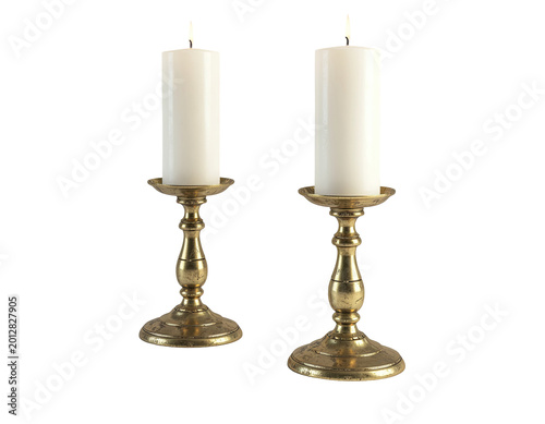 Two lit white pillar candles in ornate brass candlesticks