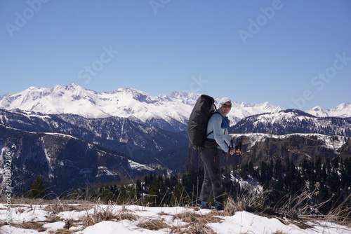 Canvas Print A male tourist with a backpack is standing in front of snow-covered mountains
