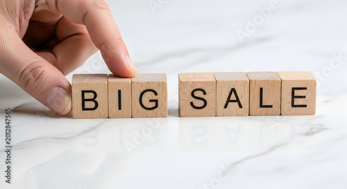 Hand arranging wooden blocks spelling big sale