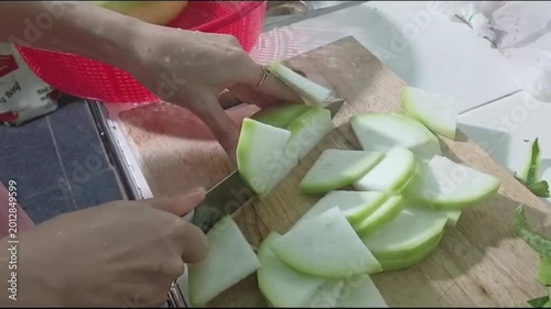 Hand Slicing Fresh Winter Melon on a Wooden Cutting Board
