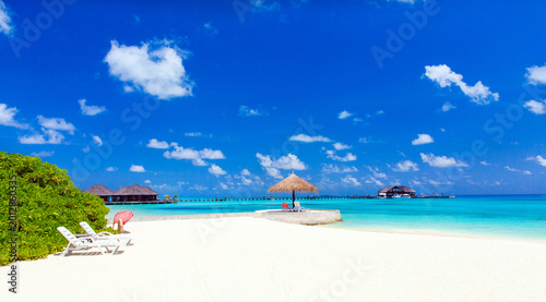 White tropical beach in Maldives with few palm trees and blue lagoon