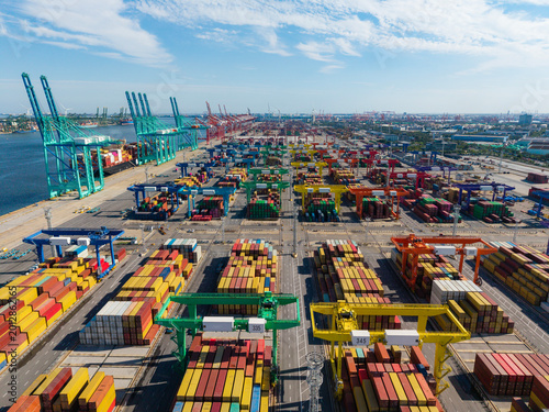 Aerial view of a large port container yard with cranes actively loading and unloading cargo