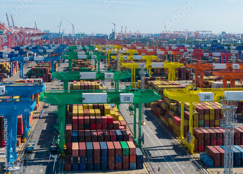 Large container port with gantry cranes in operation under clear sky