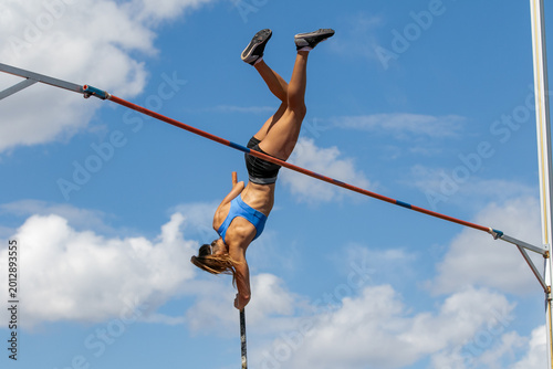 Картината върху платно Female athlete upside down with pole in hand in pole vaulting