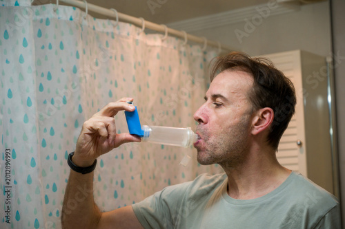 Man using asthma inhaler with spacer for respiratory relief