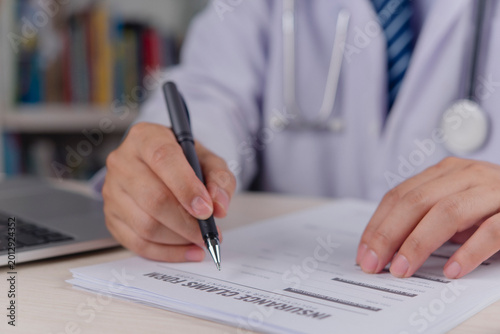 Φωτογραφία Healthcare provider signing medical chart insurance claim form clipboard pen doctor hand writing diagnostic report clinic workflow patient treatment history office desk professional service