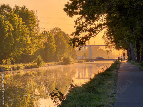 Bild auf Leinwand Golden sunset over peaceful canal with towpath in Rijkevorsel, België - serene w