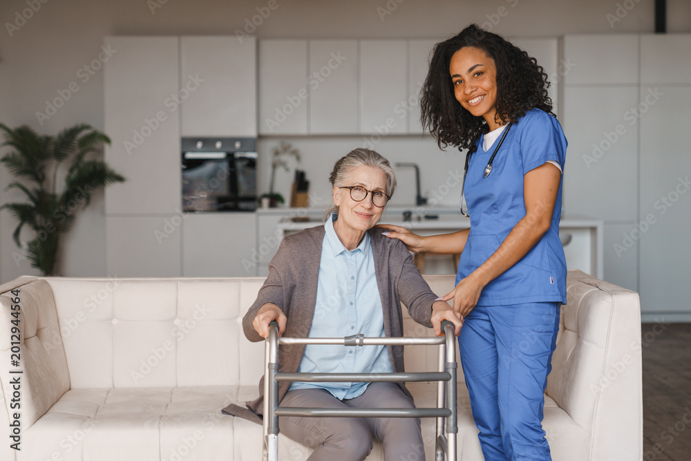 Fototapeta premium Nurse assisting senior woman with walking frame at home, elderly care, mobility support, rehabilitation, caregiver assistance, recovery and healthcare service concept
