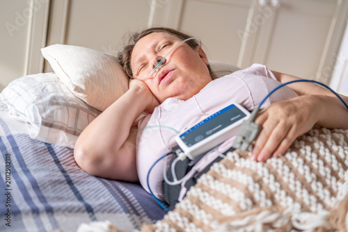 Photos Woman resting in bed with home medical monitoring device, nasal cannula oxygen,