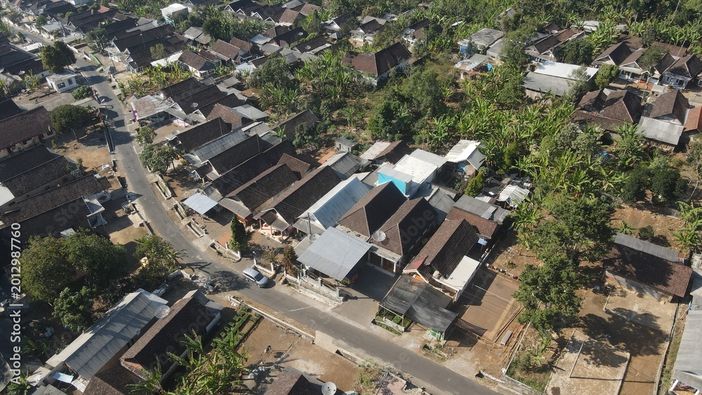 Fototapeta premium Aerial view of a peaceful rural village settlement surrounded by lush green tropical trees.