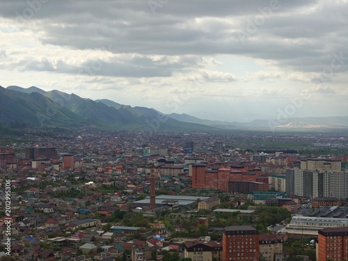 Panoramic view of a vast residential city landscape nestled beneath a range of large mountains