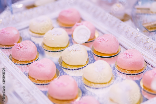 Foto Elegant pink and white petit four desserts on mirrored tray for wedding, party a